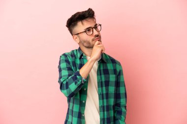 Genç beyaz adam pembe arka planda izole edilmiş ve yukarı bakıyor.