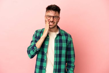 Young caucasian man isolated on pink background with toothache