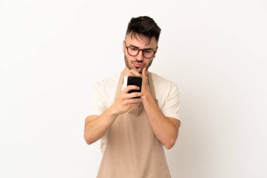 Restoran garsonu Kafkasyalı adam beyaz arka planda izole edilmiş düşünüyor ve bir mesaj gönderiyor.