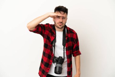 Beyaz arka planda izole edilmiş genç bir fotoğrafçı bir şeye bakmak için çok uzaklara bakıyor.