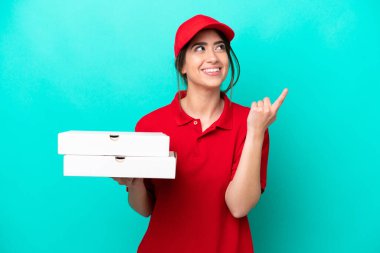 İş üniformalı bir pizzacı kadın mavi arka planda izole edilmiş pizza kutuları alıyor. Harika bir fikre işaret ediyor.
