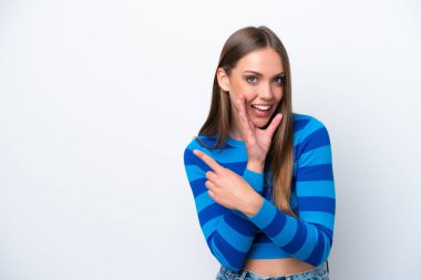 Beyaz arka planda izole edilmiş genç beyaz bir kadın bir ürünü sunmak ve bir şeyler fısıldamak için kenarı işaret ediyor.