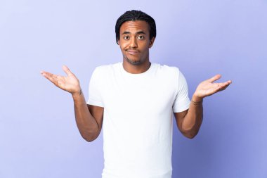 Örgülü genç Afrikalı Amerikalı adam mor arka planda izole edilmiş. Şüpheleri var ve ellerini kaldırıyor.
