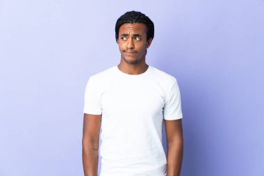 Örgülü genç Afrikalı Amerikalı adam mor arka planda izole edilmiş, yukarı bakarken şüpheleri var.