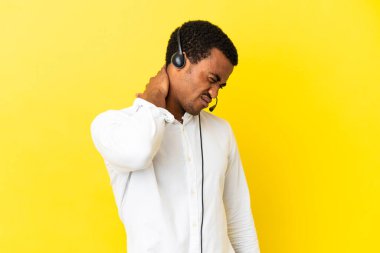 Afrikalı Amerikalı Telemarketer adam kulaklığı ile çalışıyor. İzole edilmiş sarı arka planı ve boyun ağrısı var.