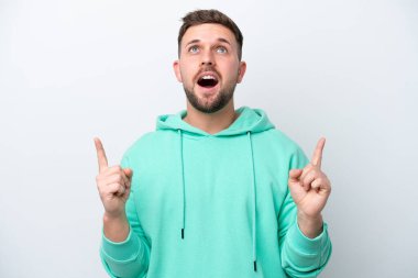 Beyaz arka planda izole edilmiş genç beyaz adam şaşırmış ve yukarı bakıyor.