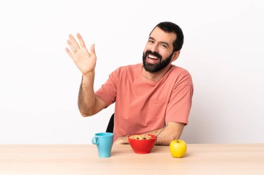 Kafkasyalı bir adam kahvaltısını yapıyor. Elinde mutlu bir ifadeyle selamlıyor..