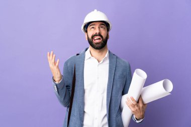 Miğferli genç bir mimar, izole edilmiş mor arka plan üzerinde planlar tutuyor.