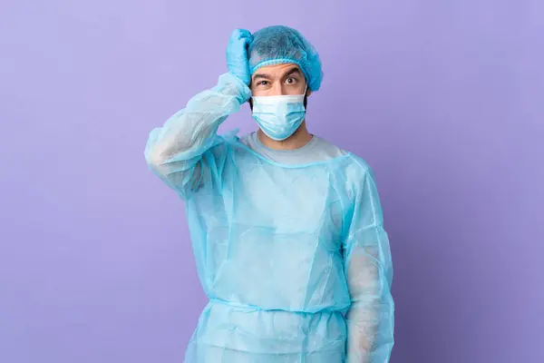Surgeon man with beard with blue uniform over isolated purple background with an expression of frustration and not understanding