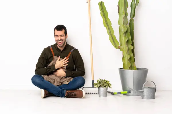 Gardener man sitting on the floor at indoors smiling a lot