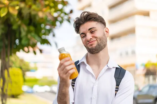 Junger Gutaussehender Mann Hält Draußen Einen Orangensaft Mit Trauriger Miene — Stockfoto