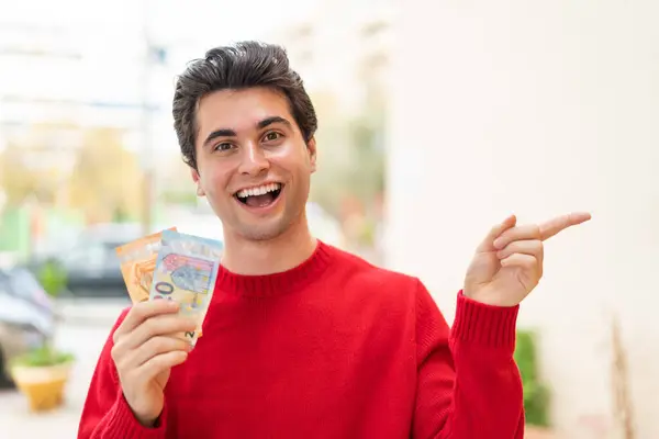 Young Handsome Man Taking Lot Money Outdoors Surprised Pointing Finger — Stock Photo, Image