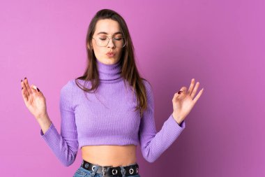 Zen pozunda, izole edilmiş mor arka planı olan genç bir kadın.