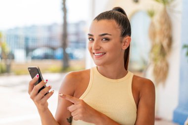 Açık havada cep telefonu kullanan genç ve güzel bir kadın.