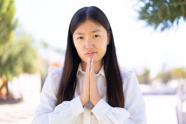 Dışarıdaki güzel Çinli kadın avuç içlerini bir arada tutuyor. İnsan bir şey ister.