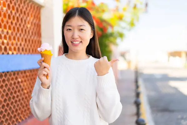 Pretty Chinese Woman Cornet Ice Cream Outdoors Pointing Side Present — Stock Photo, Image
