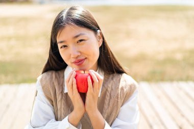 Dışarıdaki genç Çinli kadın elinde elma tutuyor.