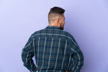 Beyaz adam, mor arka planda izole edilmiş, arka pozisyonda ve yana bakıyor.