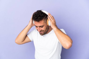 Mor arka planda izole edilmiş beyaz adam müzik dinliyor.