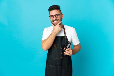 Önlüklü berber mutlu ve gülümsüyor.