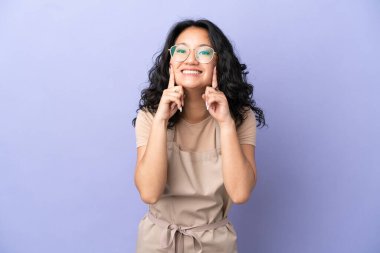 Restoran Asyalı garson, mor arka planda izole edilmiş mutlu ve hoş bir ifadeyle gülümsüyor.