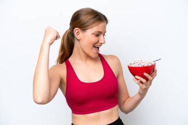 Genç, güzel sarışın kadın kahvaltı sütü içiyor. Beyaz arka planda, zaferi kutluyor.