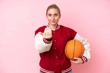Genç basketbolcu beyaz kadın, pembe arka planda izole edilmiş, bizimle gelmesi için davet ediliyor. Gelmene sevindim.