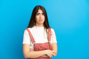 Mavi arka planda, üzgün bir ifadeyle izole edilmiş beyaz bir kadın.