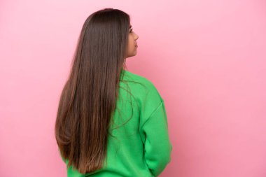 Genç beyaz kadın pembe arka planda izole edilmiş arka planda ve yan bakıyor.