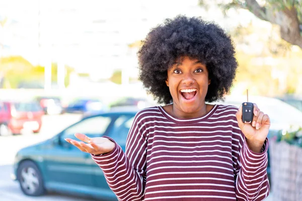 African American girl holding car keys at outdoors with shocked facial expression