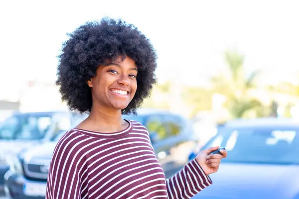 African American girl at outdoors holding car keys with happy expression