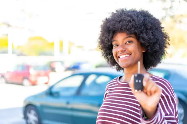 African American girl holding car keys at outdoors with happy expression
