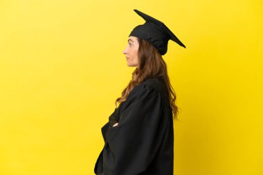 Orta yaşlı üniversite mezunu. Sarı arka planda, yan pozisyonda izole edilmiş.