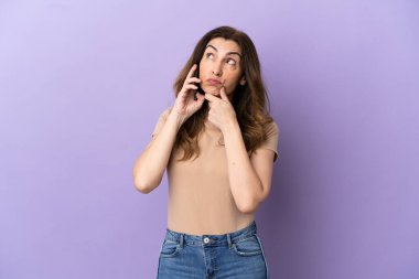 Mor arka planda izole edilmiş cep telefonu kullanan orta yaşlı beyaz kadın şüpheleri var.