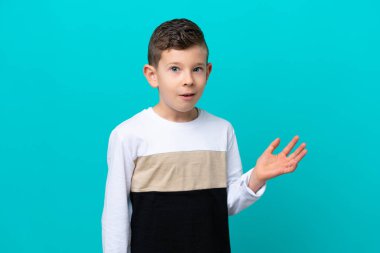 Küçük çocuk mavi arka planda izole edilmiş şüpheli hareketler yapıyor.