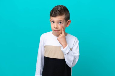 Küçük çocuk mavi arka planda izole edilmiş bir şey gösteriyor.