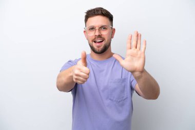 Beyaz arka planda izole edilmiş beyaz tenli genç adam parmakları olan altı kişi sayıyor.