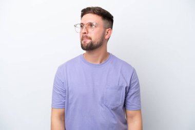 Beyaz arka planda izole edilmiş genç beyaz adam yukarı bakarken şüpheleri var.