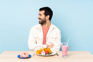 Masada waffle yiyen ve milkshake içen bir adam.