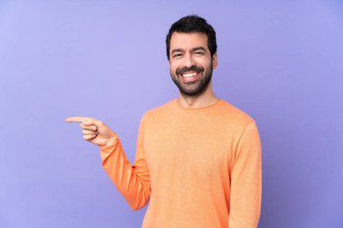 İzole edilmiş mor arka planda beyaz, yakışıklı bir adam parmak işareti yapıyor.