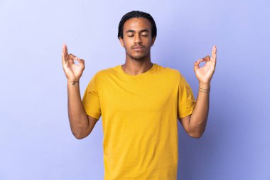Örgülü genç Afrikalı Amerikalı adam. Mor arka planda Zen pozisyonunda izole edilmiş adam.