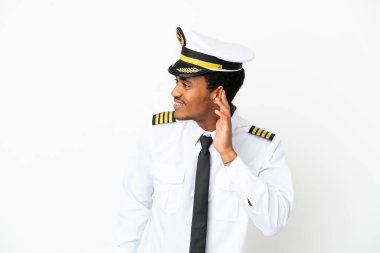 İzole edilmiş beyaz arka plan üzerinde Afrikalı Amerikan Uçak Pilotu bir şey dinlemek için elini kulağına koydu
