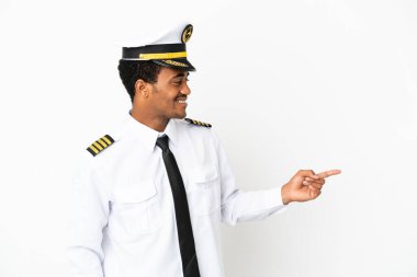 İzole edilmiş beyaz arka plan üzerinde Afrika Amerikan Uçak Pilotu parmağını yana doğru uzattı ve bir ürün sundu.