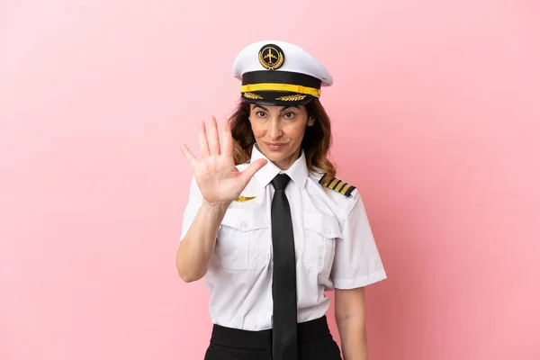 Airplane middle aged pilot woman isolated on pink background counting five with fingers