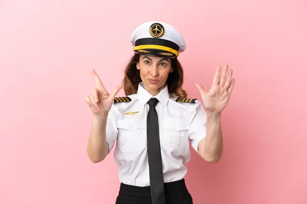 Airplane middle aged pilot woman isolated on pink background counting seven with fingers
