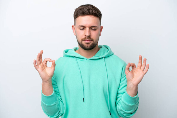 Young caucasian man isolated on white background in zen pose
