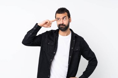 Sakallı genç adam izole edilmiş beyaz arka planda deliliğin hareketini yapıyor. Parmağını kafaya koyuyor.