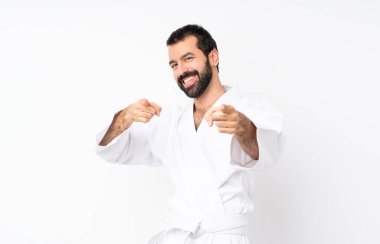 İzole edilmiş beyaz arka planda karate yapan genç adam gülümserken seni işaret ediyor.