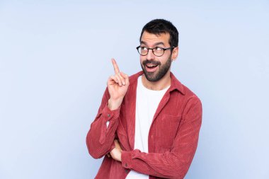 Mavi arka planda kadife ceket giyen genç beyaz bir adam bir fikir düşünüyor.