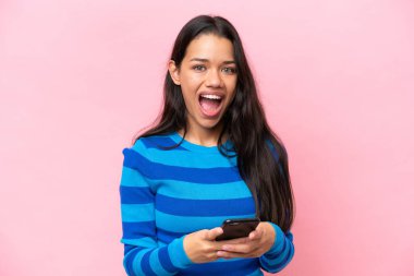 Young Colombian woman isolated on pink background surprised and sending a message